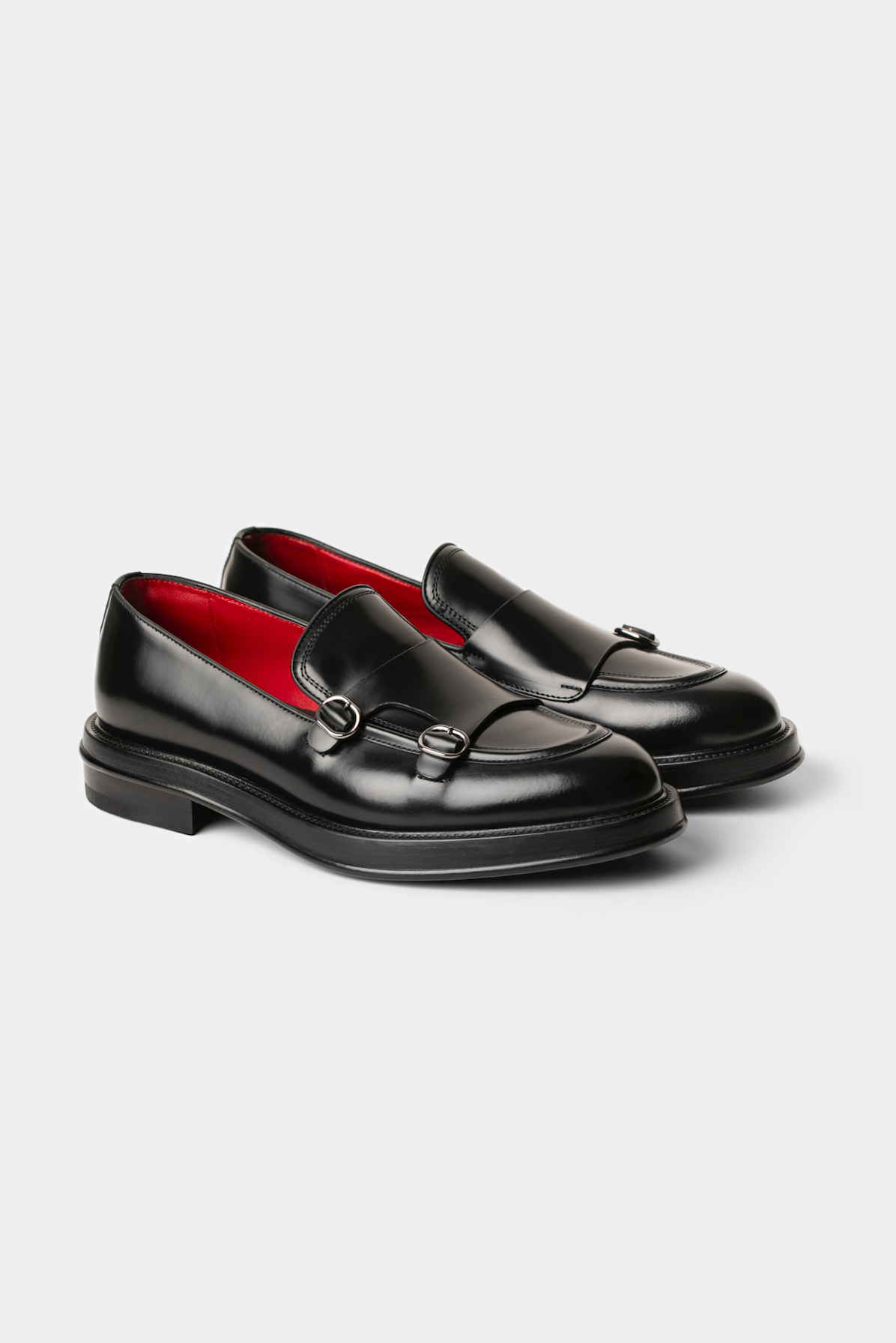 Pair of black loafers with red interior on a light gray background